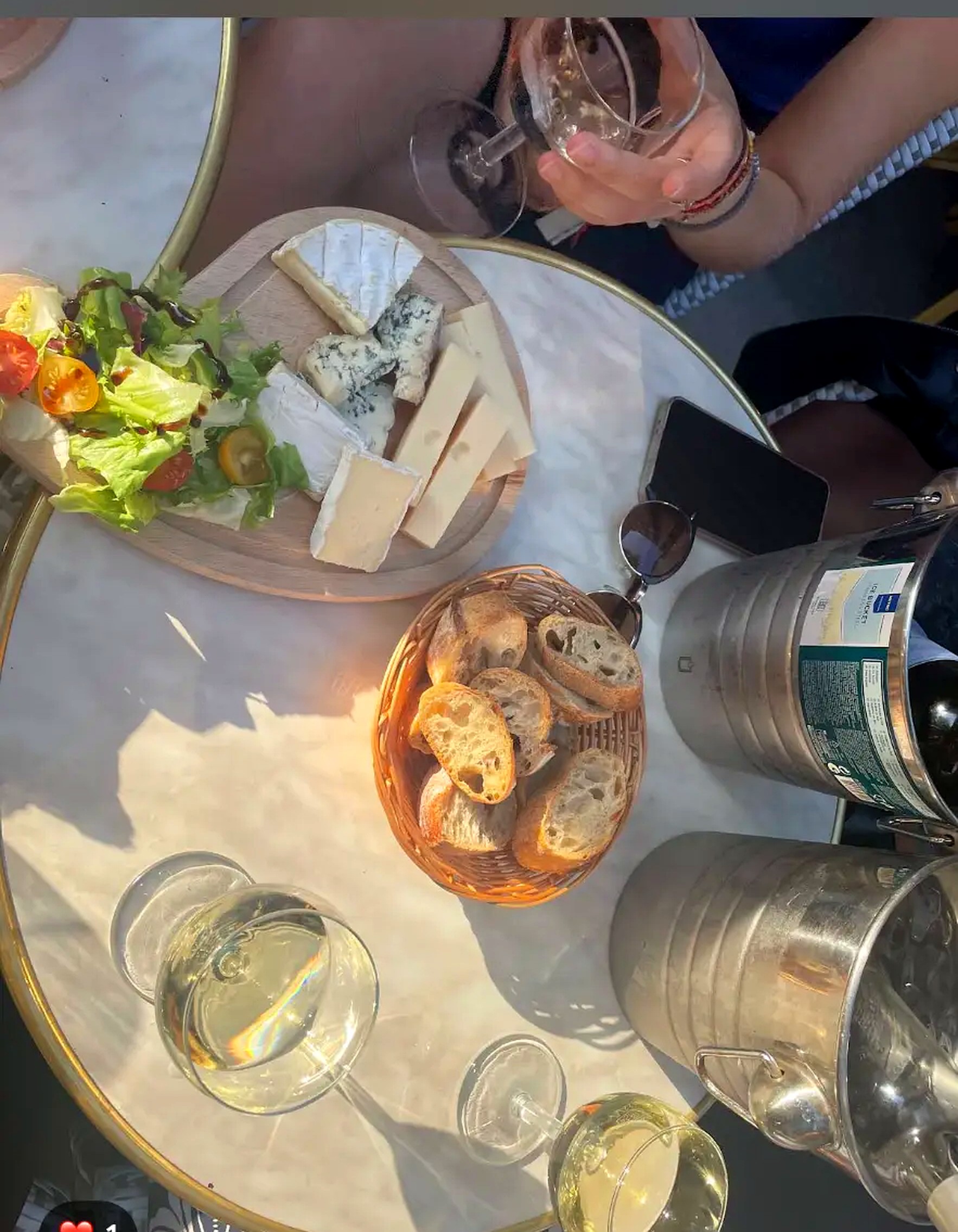 Plateau de fromages, corbeille de pain et vins blancs au soleil